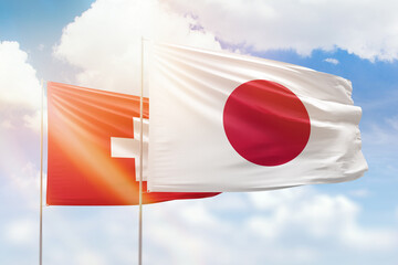 Sunny blue sky and flags of japan and switzerland