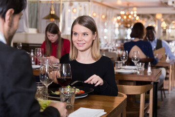 Attractive girl with boyfriend enjoying evening meal in cozy restaurant