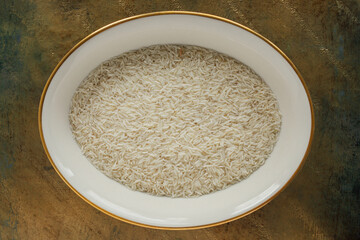dry, raw Basmati rice grains in dish on golden surface