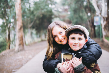 Single mother hugging her young son in the park. Single parent family