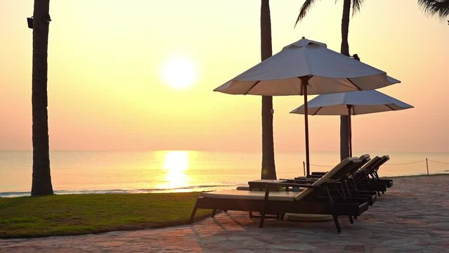 A pink and yellow ocean sunset lights up the beach and the empty sun lounges. Title space