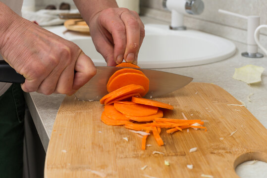 Chefs hands chopping carrot on wooden board - Powered by Adobe