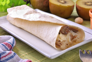Creamy chicken with mushroom burrito on white plate