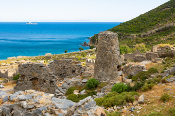 Fototapeta na wymiar Scenic view of stone ruins of necropolis in ancient city of Anemurium on hillside on background of blue water of Mediterranean Sea on sunny spring day, Mersin province. Archaeological sites of Turkey