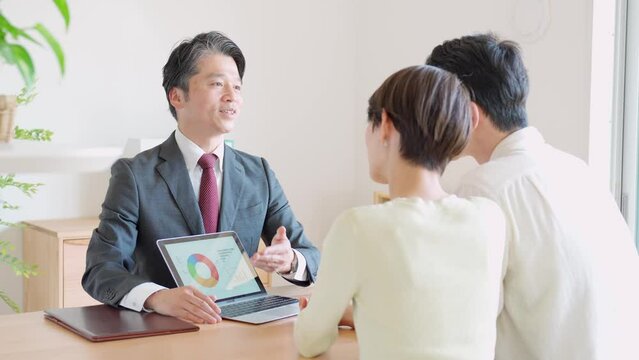 パソコンを使って説明する笑顔のビジネスマンと日本人男女