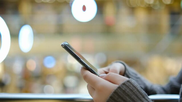 Shopping center. Moll. Finger of woman touching scroll page app on mobile phone. Browsing movie video in the internet library to watch film online.