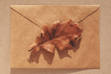 Oak leaf on brown paper envelope, minimal fall background, autumn flat lay