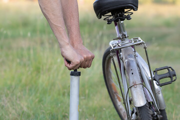 Men's hands inflate a bicycle wheel with an autonomous hand pump.Walk on a rare bike in the village. - Powered by Adobe