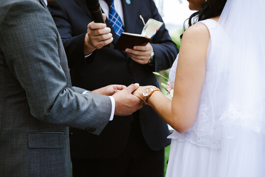 Novio poniendo el anillo en mano de la novia mientras promete amor eterno
