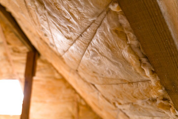 The roof is insulated with yellow glass wool. Insulation hemming with thread, close-up