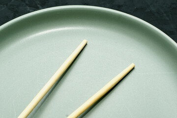 grey plate and chopsticks on a black background