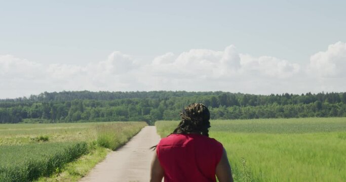 Samson walking away from screen into distance along old road in green pastures, Biblical character with long dreads, Israelite warrior and judge, black male in old testament, Christian