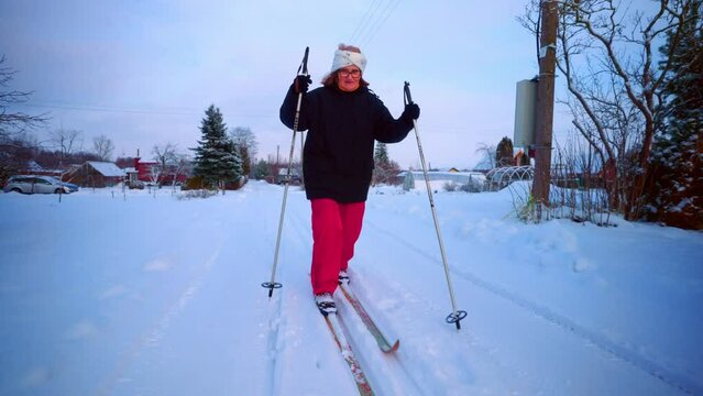 Skiing Aged Woman On The Countryside Village In Winter Landscape. Slow Motion
