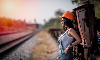 Portrait beautiful woman coal worker showed working near railway station with orange helmet and...