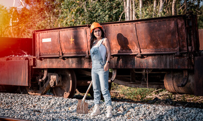 Portrait beautiful woman coal worker showed working near railway station with orange helmet and shoveling coal