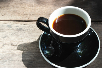 Top view of hot Amerucano coffee in black ceramic cup on wooden background.