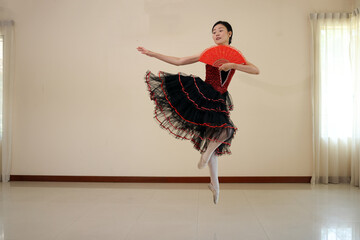 Beautiful Asian woman ballet dancer practice dance jump move wearing tutu at home