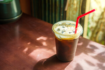 Close-up of Americano ice coffee or black coffee in cup mug on glass wood desk office desk in coffee shop at the cafe in garden,during business work concept
