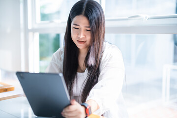 Obraz premium asian freelance people business female wearing smartwatch talking making using casual working with tablet for browsing internet, chatting and blogging and smartphone,notebook in coffee shop.
