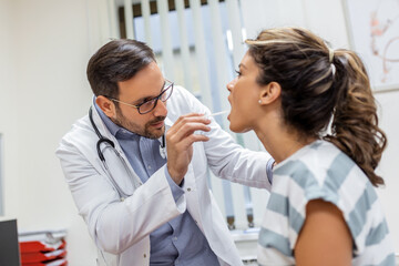 Doctor using inspection spatula to examine patient throat. ENT doctor doing throat exam of a woman....