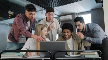 Young corporate employees sitting in office looking at laptop screen reading good news excited happy team diverse people celebrating victory win command success excellent result professional teamwork