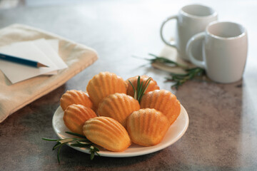Petite madeleine on plate and cup of coffee in background.
