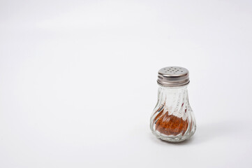 Glass container with a metal screw-on lid with holes for ground pepper.