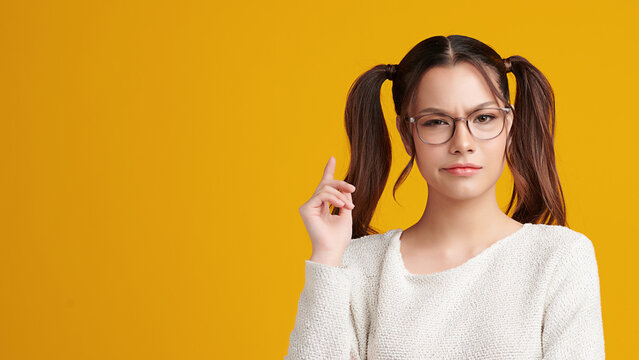Curious Asian girl is thinking and standing on yellow background with curious face, blank copy space for your advertising content.