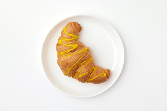 Top view image of french croissant with glaze served at plate isolated at white background.