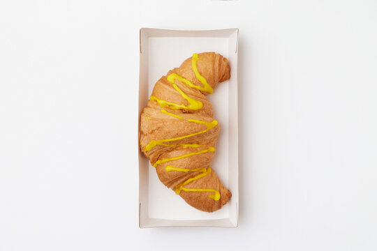 Top view image of french croissant with glaze served in a cardboard box isolated at white background.