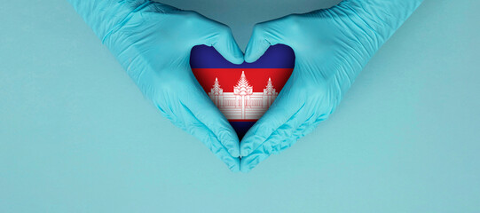 Doctors hands wearing blue surgical gloves making hear shape symbol with cambodia flag