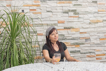Fototapeta na wymiar Mexican woman sitting drinking a beverage on the patio.