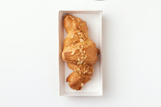 Top view image of french croissant with paenuts served in a cardboard box isolated at white background.