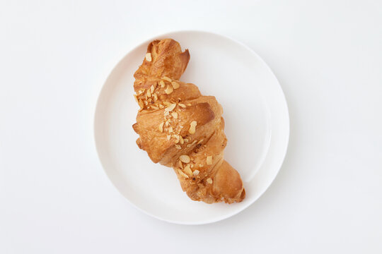 Top view image of french croissant with peanuts served at plate isolated at white background.