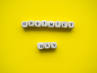 world optimist day. Yellow background with text Optimist Day on wooden cubes and with place for...