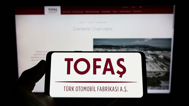 Stuttgart, Germany - 06-11-2022: Person holding smartphone with logo of car manufacturer Turk Otomobil Fabrikasi (Tofas) on screen in front of website. Focus on phone display.
