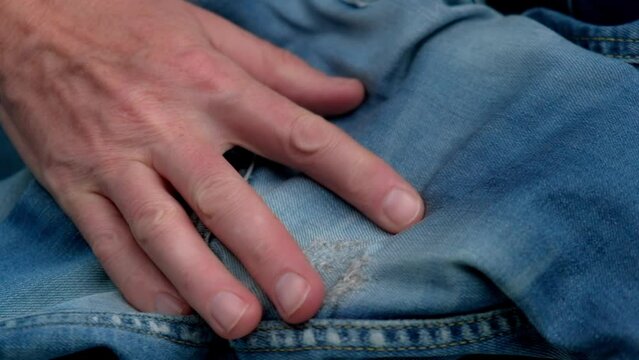 tailor checks quality of darning holes rubbed between legs on women's jeans.close-up of hands examining quality of sewing repair holes on jeans.concept of clothing repair or waste recycling.slowmotion