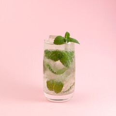 Mojito cocktail. Refreshing summer drink. Pink background, selective focus. Homemade iced drink with lemon, lime and mint leaves