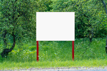 White empty signboard with space for mockup stands on summer garden. Information blank banner on...