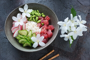 Grey bowl with hawaiian ahi poke on a dark-grey stone background, elevated view, horizontal shot