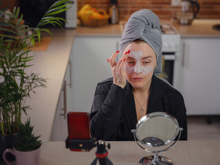 Famous blogger. Cheerful female vlogger showing beauty mask while recording video and giving tips for her beauty blog. Woman testing new product. cosmetic face mask