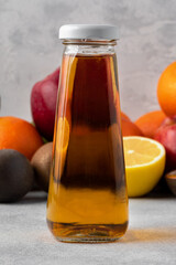 Various fruits and freshly squeezed fruits juice in bottle on gray background