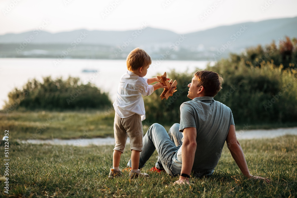 Wall mural dad and son play on the seashore, vacation with children. Summer adventure, fun trip with kids. Fatherhood, Father's Day. Happy family travel and vacation concept