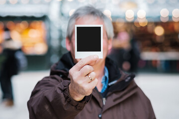 älterer Mann hält Polaroid Foto in der Hand