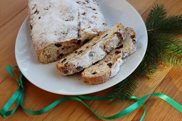 Traditional german sweet bread with raisins and candied fruits called Stollen on a plate on wooden table 