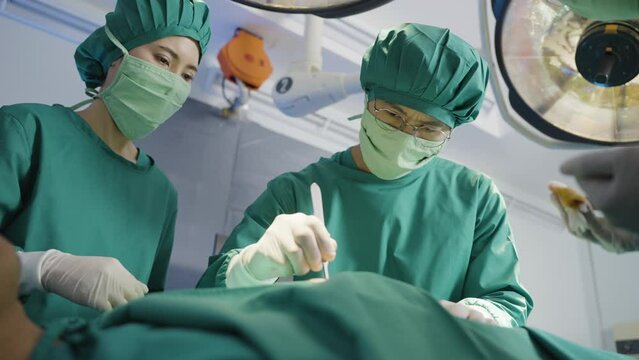Asian doctor uses a scalpel to the patient with surgical team in operating room