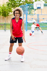 Obraz premium girl with afro hairstyle with a ball on a basketball court