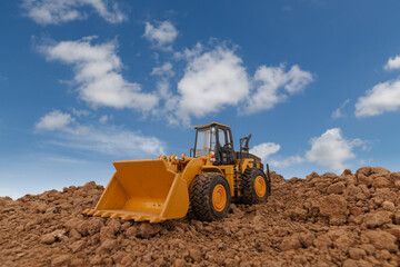 Wheel loader are digging the soil in the construction site on sky and cloud background .