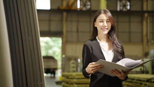 Portrait of Asian young woman factory quality inspector hold document folder and looking at camera