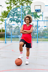Obraz premium girl with afro hairstyle with a ball on a basketball court